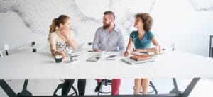Three people at a desk with computers
