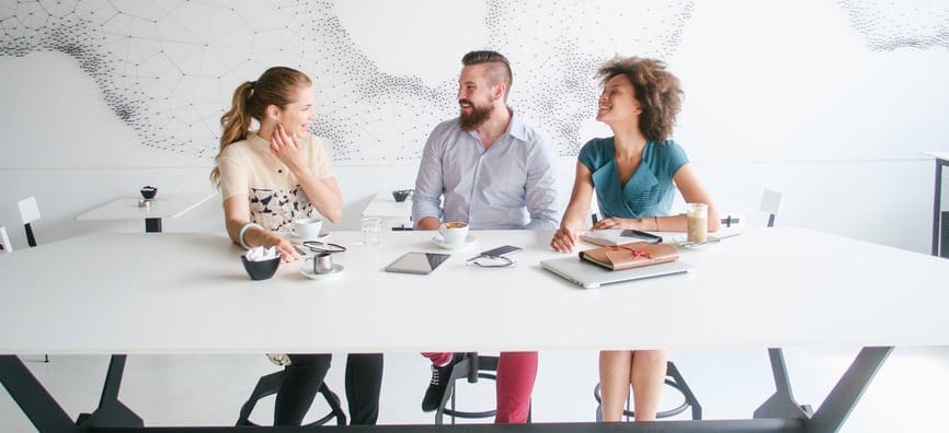 Three people at a desk with computers