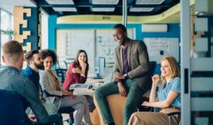 Six people discussing work in front of computers