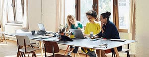 Three women looking at something on a laptop
